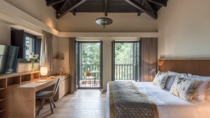 Ein Schlafzimmer mit Holztisch, einem Bett mit gemusterten Kissen und einem Balkon mit Stuhl und Tisch.