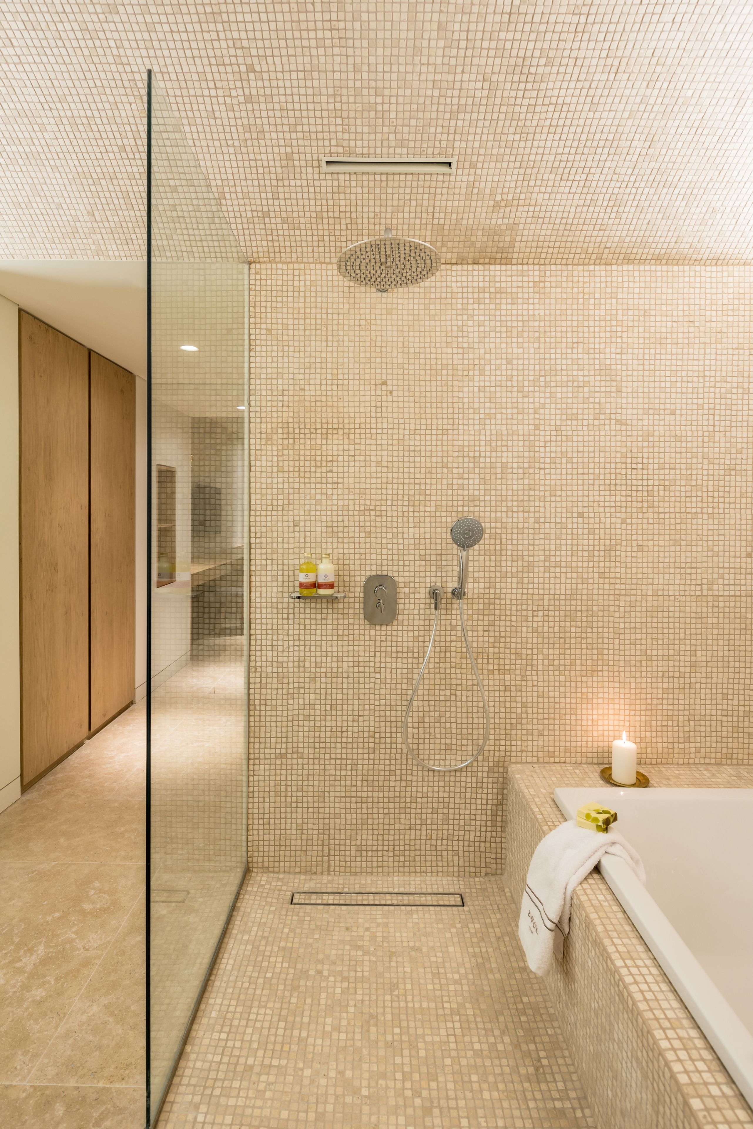Un baño moderno con ducha envuelta en cristal, bañera y suelo de baldosas.