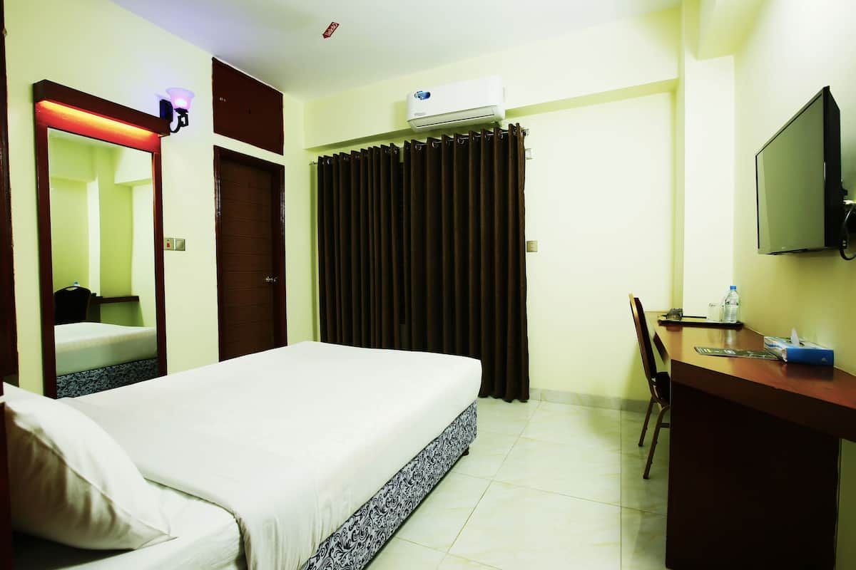 Une chambre d’hôtel équipée d’un lit, d’un bureau, d’une chaise, d’une télévision et d’un appareil de climatisation.