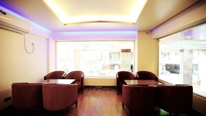 A conference room with a wooden floor, red upholstered chairs, and a large window offering a view of the outside.