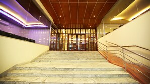 A marble staircase with a wooden ceiling and glass doors at the top.