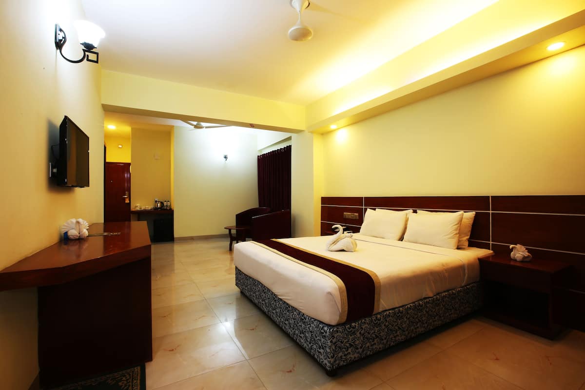 Une chambre d’hôtel avec un grand lit, un bureau, un téléviseur à écran plat et une salle de bain visible au fond.