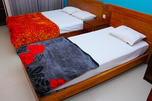Two single beds with wooden headboards, white bedding, and a grey floral blanket on one bed. - Shopno Bilash Holiday Suites (Cox's Bazar)