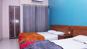 Une chambre d’hôtel avec deux lits, une tête de lit en bois, un rideau gris et un appareil de climatisation.