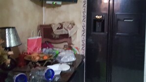 A kitchen with a TV mounted on the wall, a refrigerator, and various items on the counter. - Appartement Rashed (Tunis)