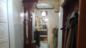 A narrow hallway with a floral carpet, a wooden door, and a mirror on the wall. - Appartement Rashed (Tunis)