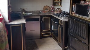 A compact kitchen with dark wooden cabinets, a stainless steel range, and a built-in oven. - Appartement Rashed (Tunis)