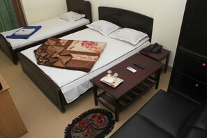 Habitación de hotel con dos camas individuales, una mesita con un control remoto, una botella y una bandeja con vasos.