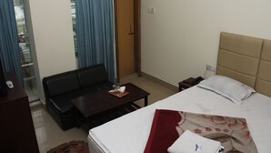 Une chambre d’hôtel avec un lit, un canapé, une petite table et une table de chevet.