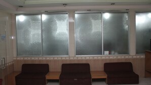 Un espace d’attente comprenant trois bancs rembourrés et des fenêtres en verre dépoli.