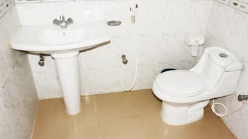 Casa de banho com lavatório branco, sanita e dispensador de toalhas.