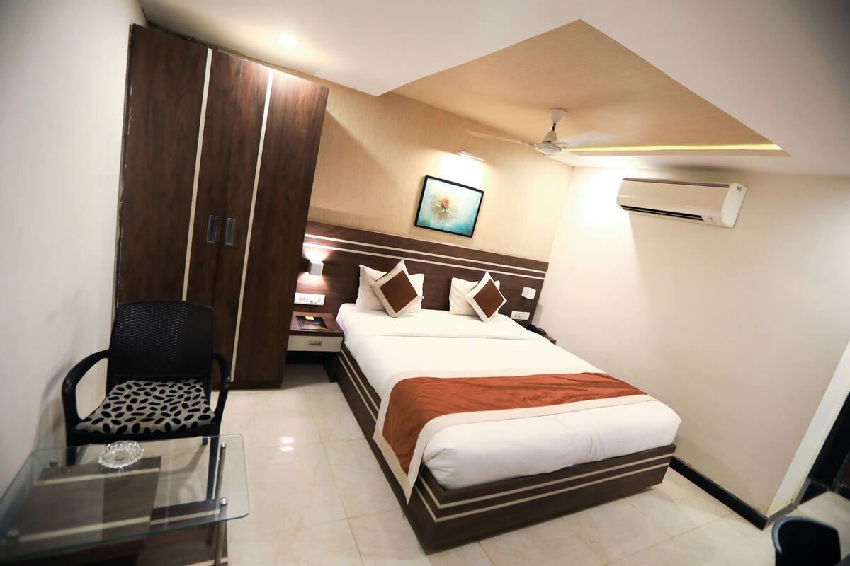 A bedroom with a bed, a chair, a wardrobe, and a ceiling fan.