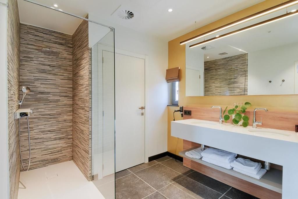 Un baño moderno con cabina de ducha de vidrio, tocador de madera y un espejo grande.