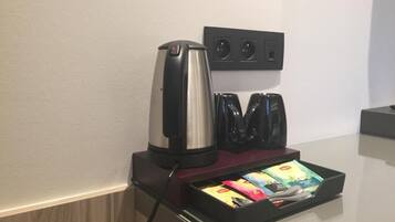 A coffee machine, a set of black chargers, and a tray with colorful items on a counter.