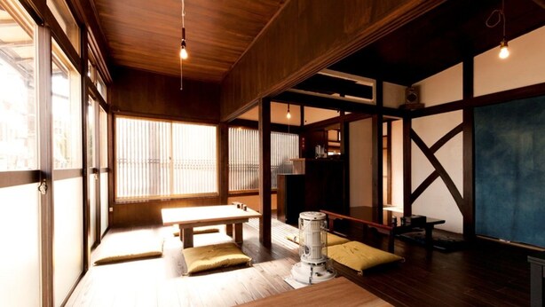 Una habitación japonesa tradicional con suelo de tatami, una mesa baja, cojines y un calentador.