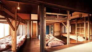Una habitación rústica con vigas de madera, literas y una escalera.