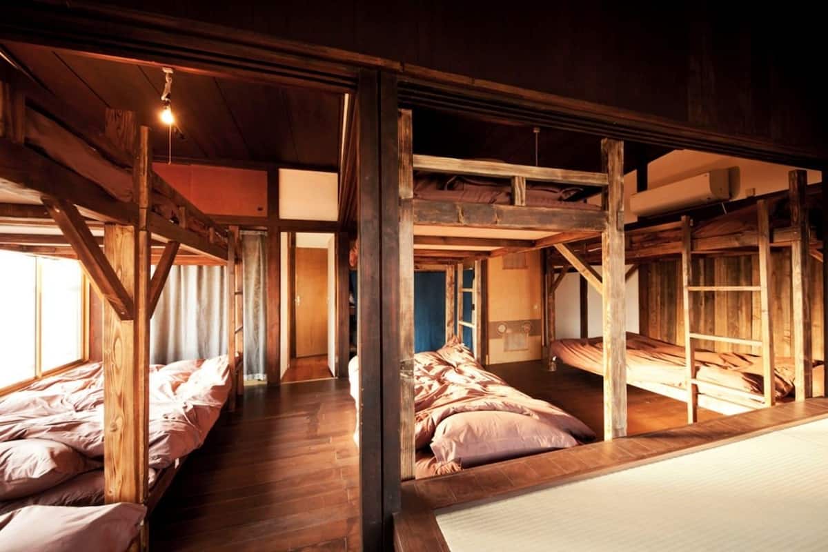 A rustic room with wooden beams, bunk beds, and a ladder.