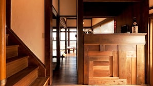 Un interior japonés tradicional con suelo de madera, una escalera y un mostrador con una botella.
