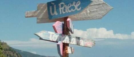 A wooden signpost with multiple directional arrows on a beach, pointing to various destinations.