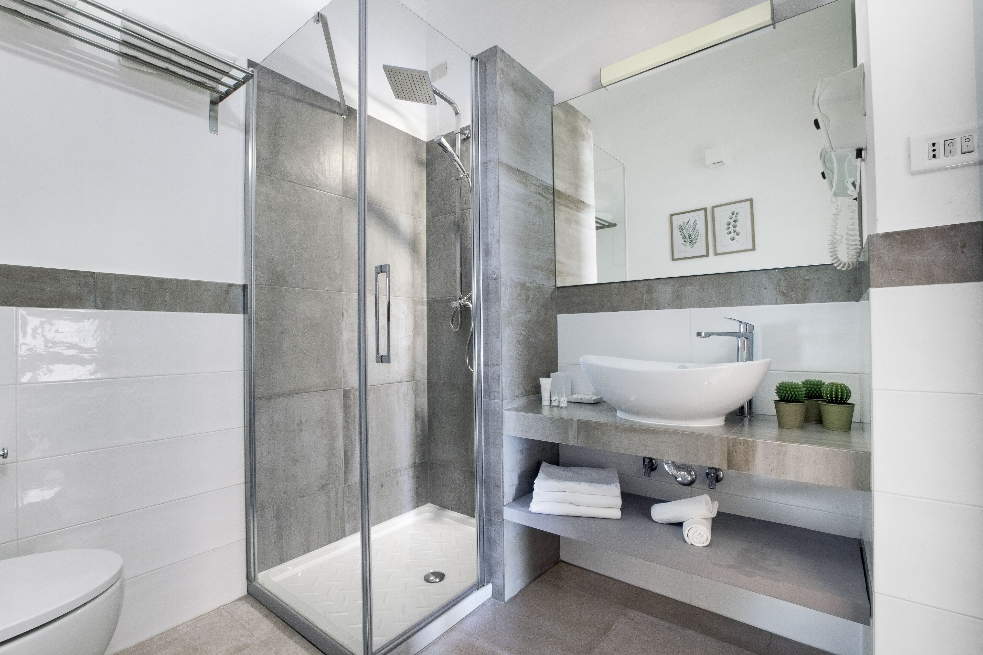 A modern bathroom with a glass-enclosed shower, a white sink, and a toilet.