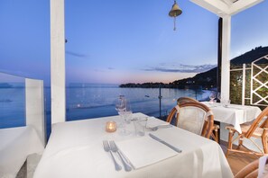 Mesa posta para refeição com vista para o mar e um sino em cima.