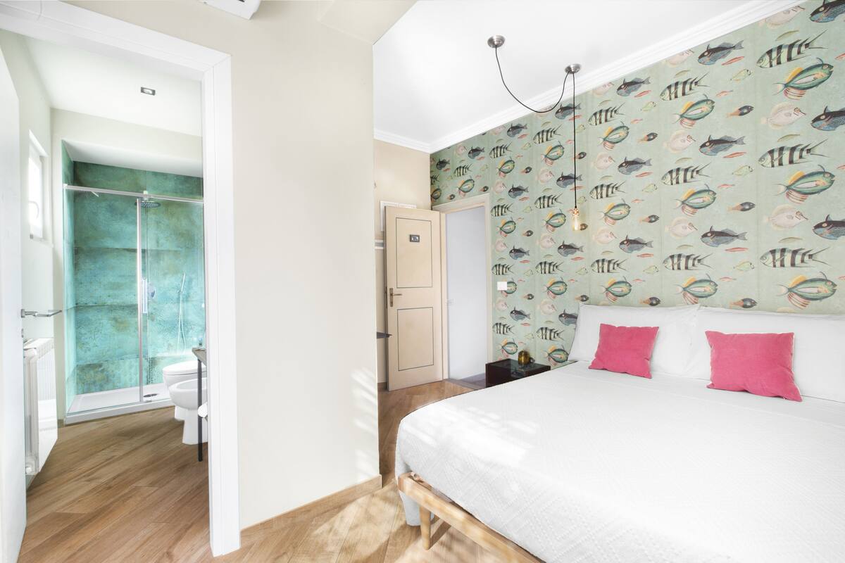 A bedroom with a bed, a shower, and a bathroom.