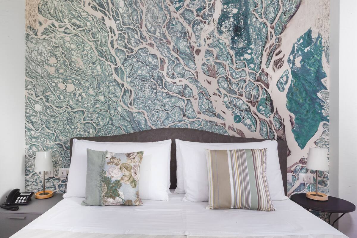 A bed with white linens, a dark headboard, and two bedside tables with lamps.