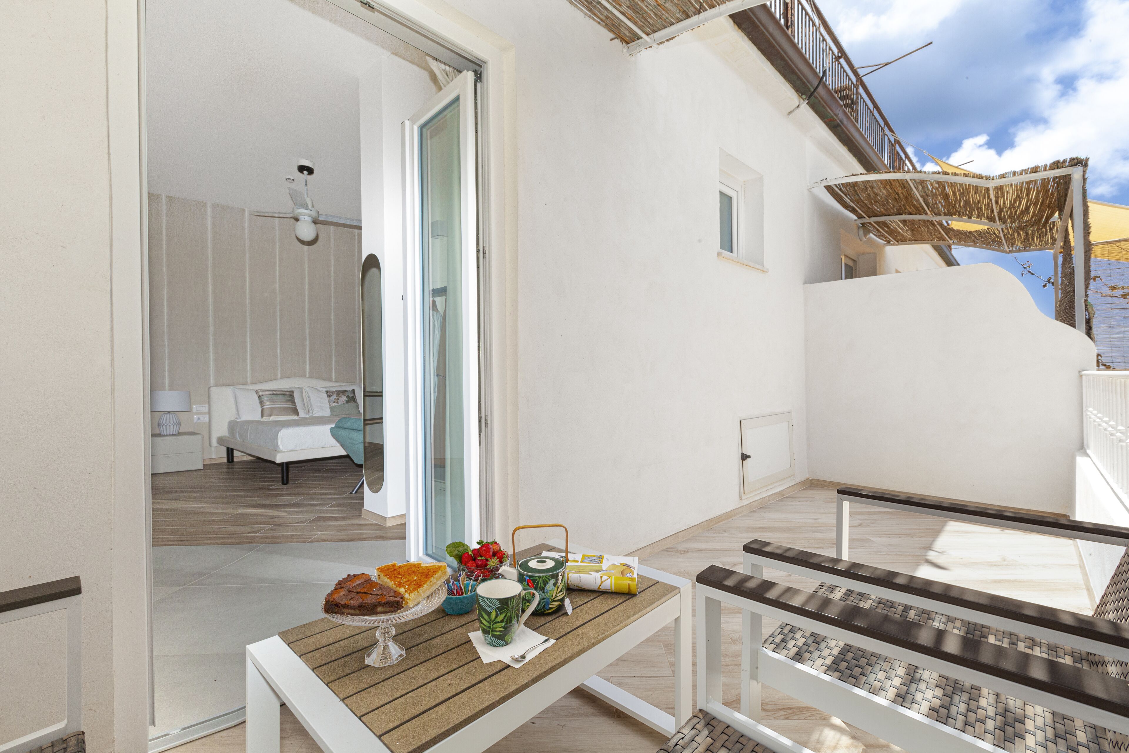 En balkon med et morgenmadsbord, en sofa og udsigt over indretningen.
