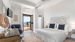 A hotel room with a bed, a desk, a chair, a television, and a view of the ocean. - Hotel Il Cefalo (Castellabate)