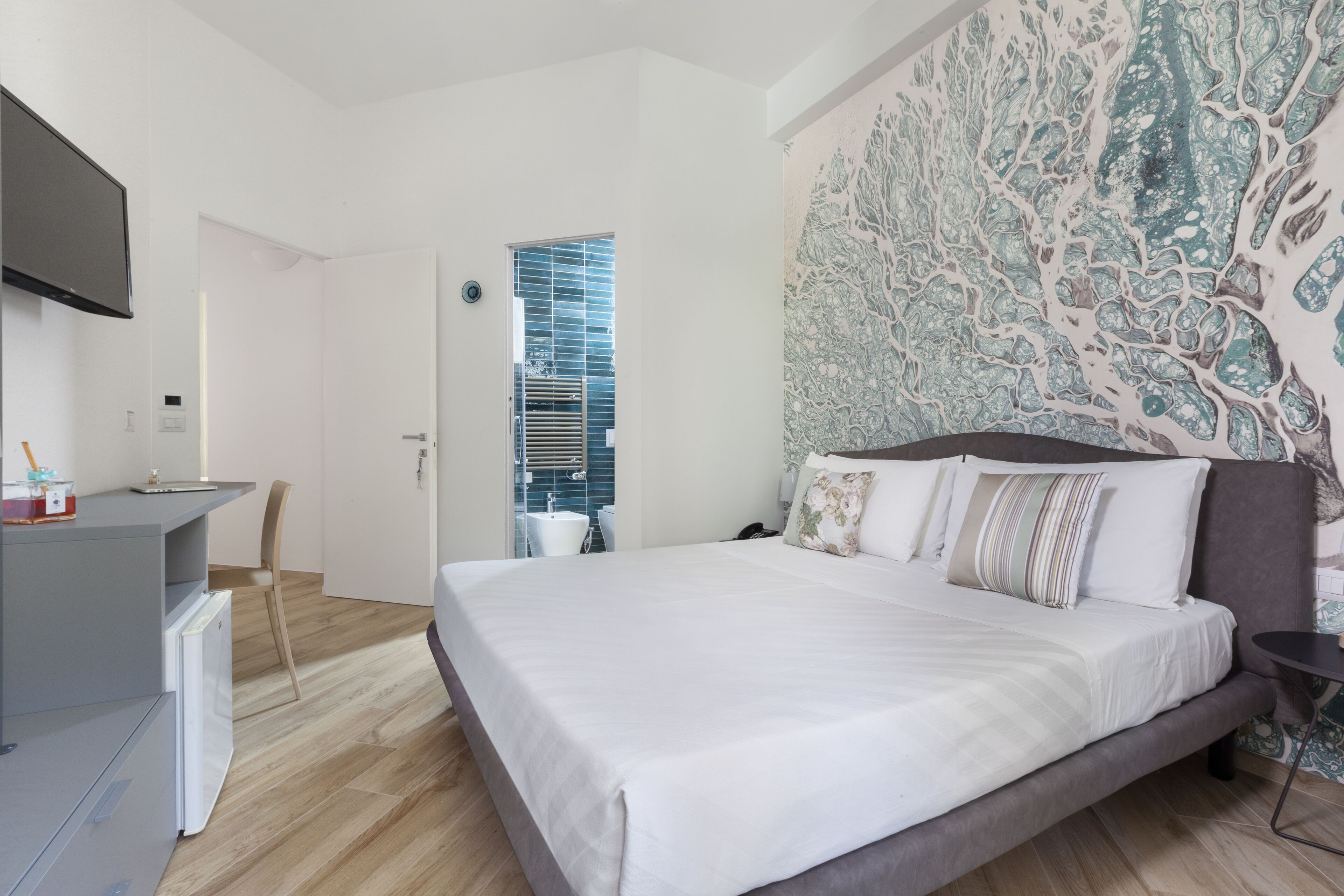 A modern hotel room with a large bed, a desk, and a television.