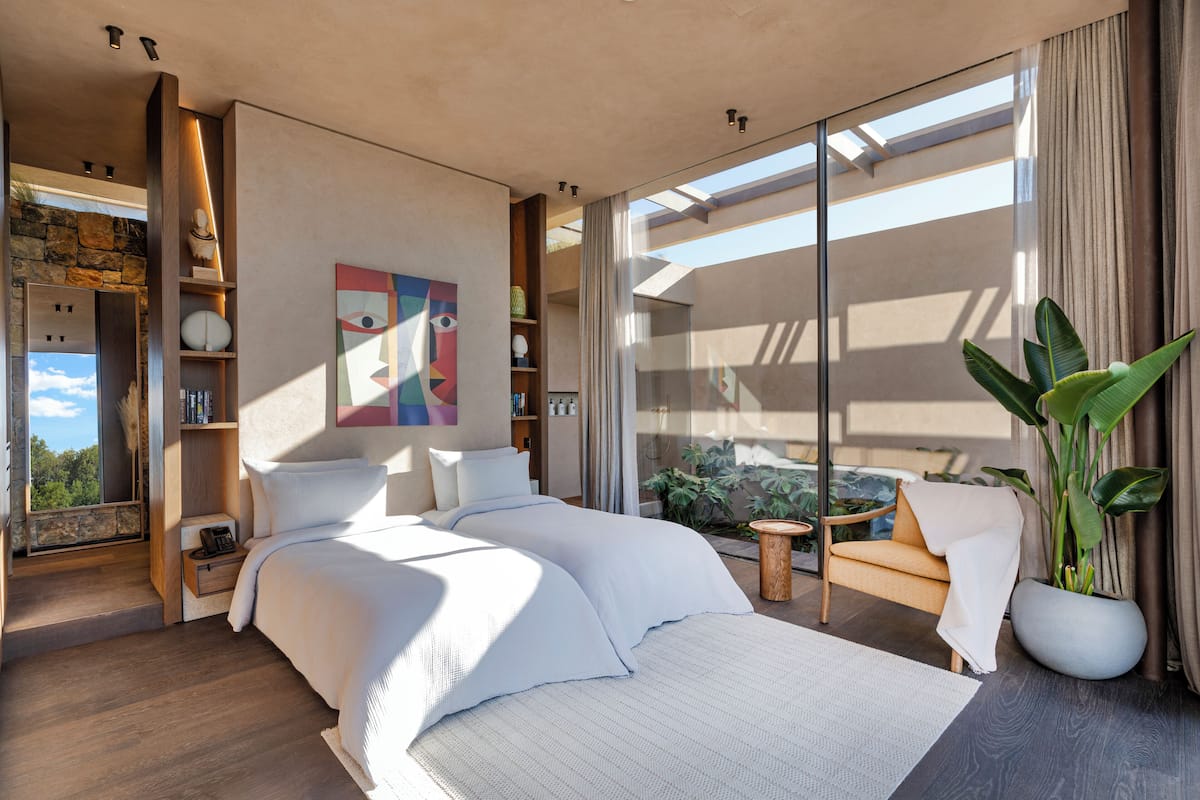 Un dormitorio moderno con una cama grande, una zona de estar y vistas al exterior.