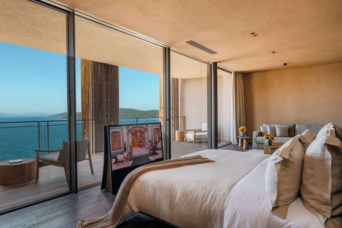 Un moderno cuarto de hotel con una cama grande, un balcón con vista al mar y un cuadro en la pared.