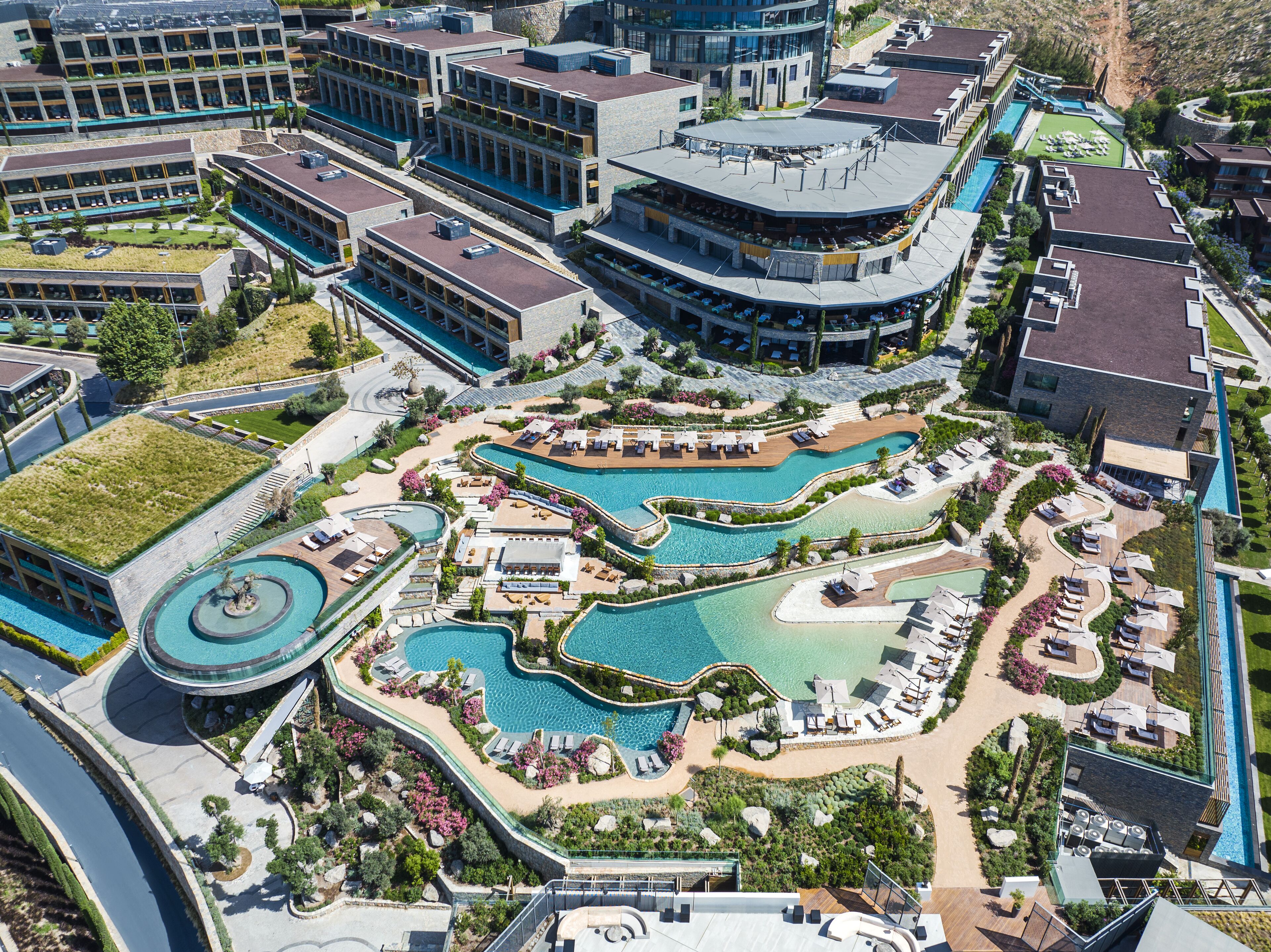 A resort with multiple swimming pools, sun loungers, and a landscaped garden area.