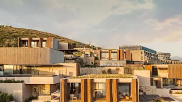 A modern resort with multiple buildings, outdoor pools, and a hillside backdrop.