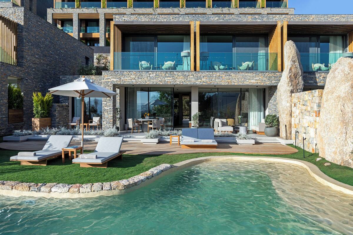Una casa moderna con piscina, mobiliario exterior y fachada de piedra.