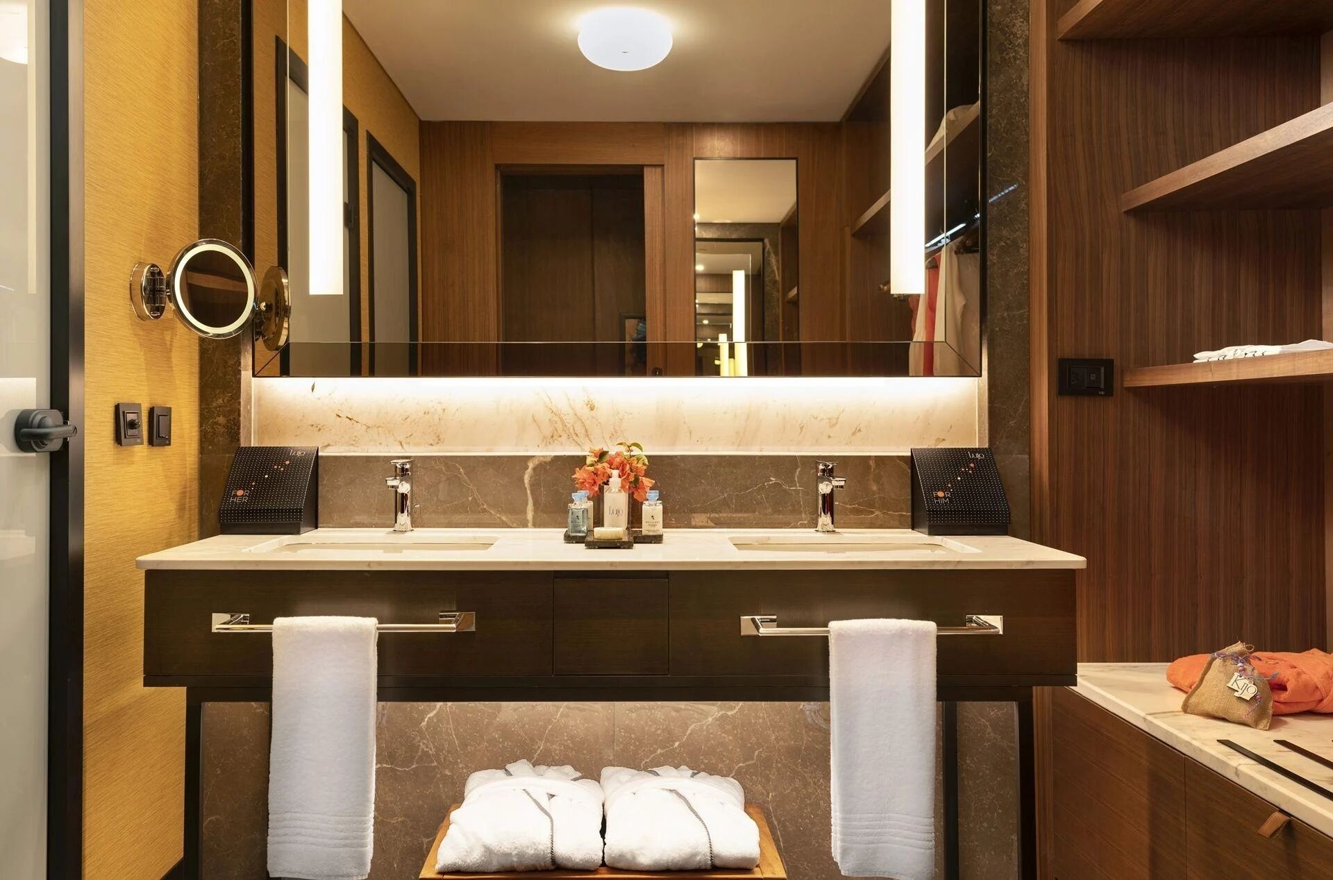 Un baño moderno con un espejo grande, dos lavamanos y una zona de tocador.