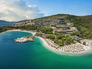 An aerial view of a coastal resort with a marina, beach, and hotel buildings.