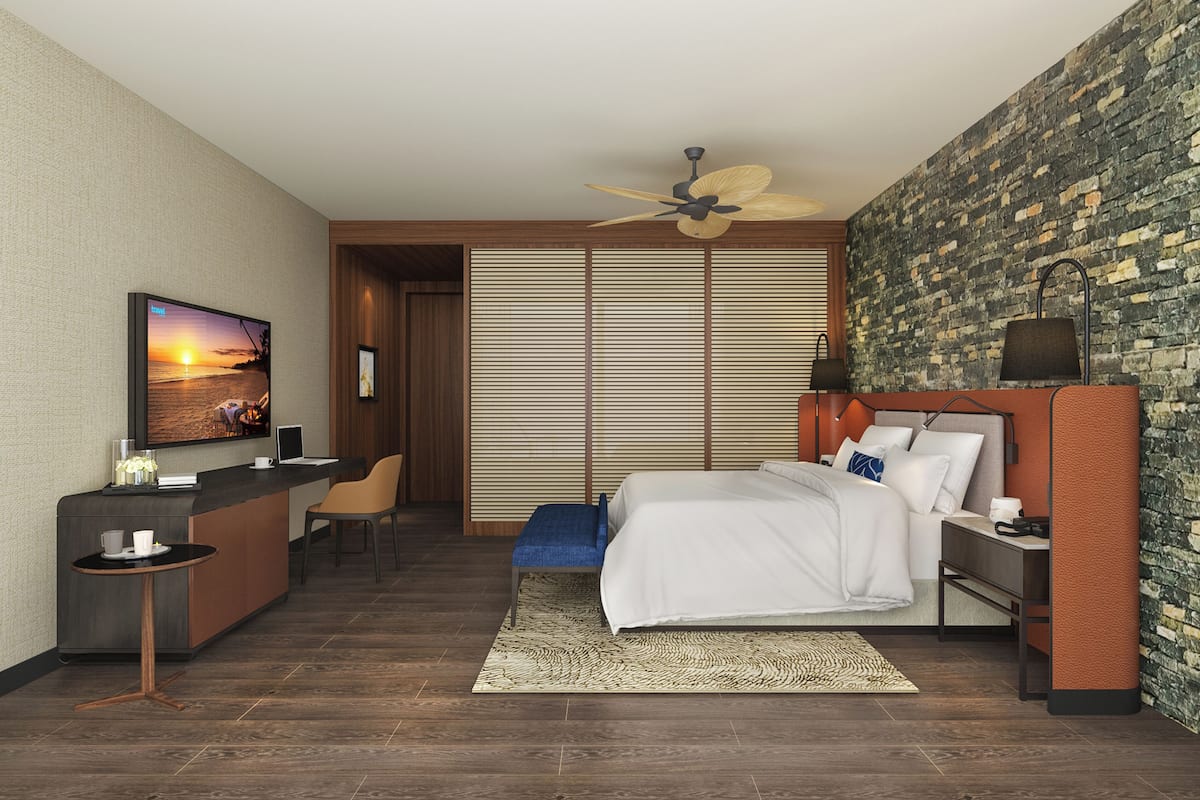 Una habitación de hotel moderna con una cama, un escritorio, una silla, un televisor y un ventilador de techo.