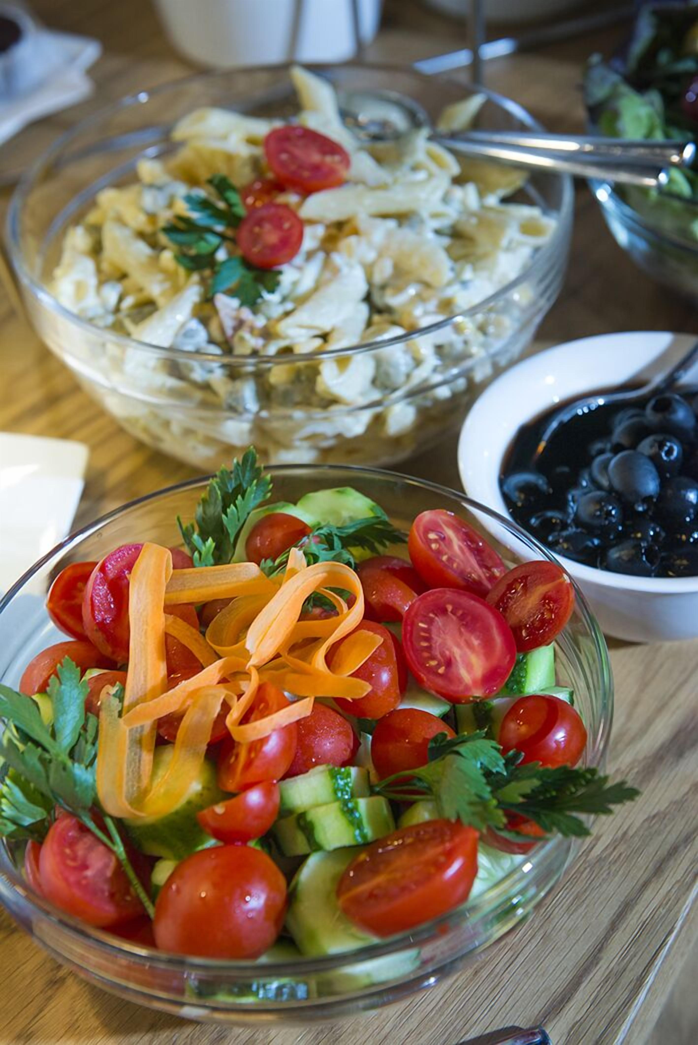A table with a salad bowl, a pasta salad bowl, and a bowl of blueberries.