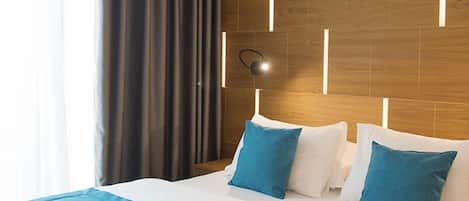 Una habitación de hotel con una cama grande, un cabecero de madera y una lámpara moderna.