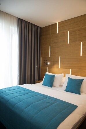 Ein Hotelzimmer mit einem großen Bett, einem Holz-Kopfteil und einer modernen Lampe.