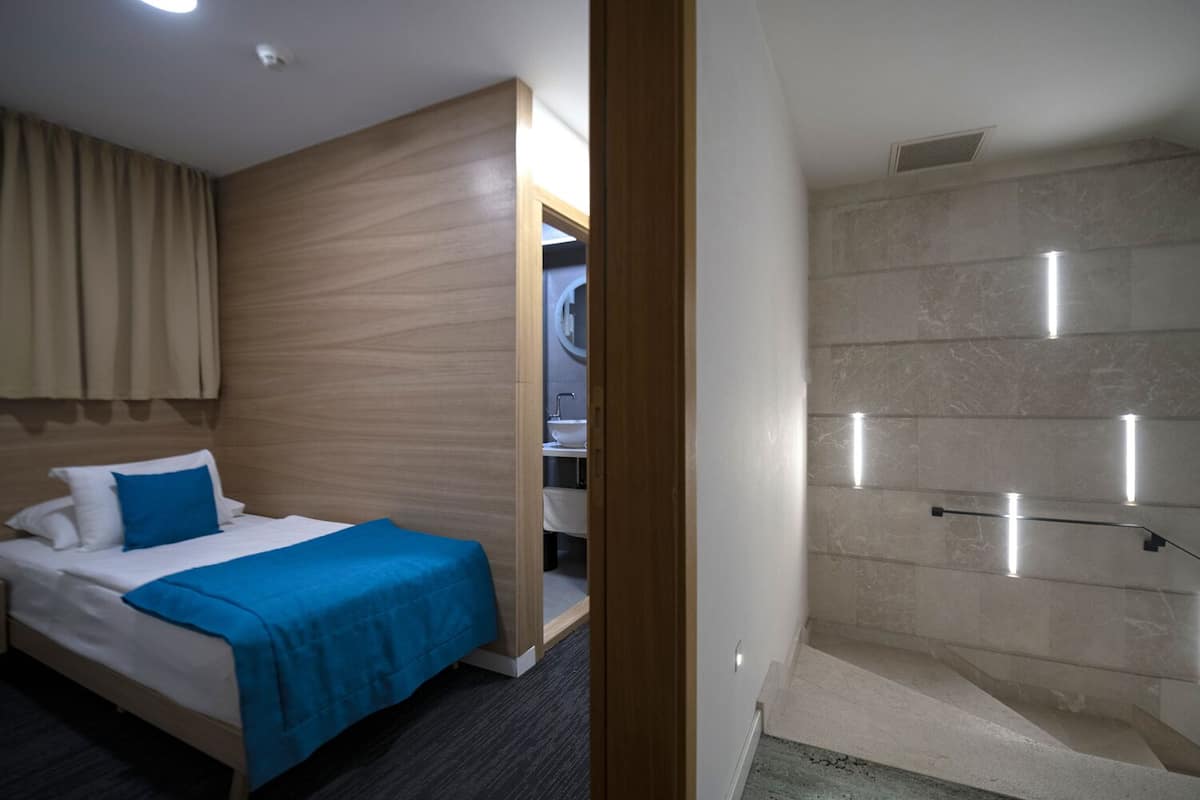 A hotel room with a bed, a shower area, and a bathroom.