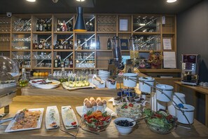 Ein reichhaltiges Buffet mit verschiedenen Speisen und einer Weinauswahl mit Gläsern im Hintergrund.