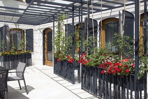 Ein Außenbereich mit Tischen und Stühlen, umgeben von schwarzen Metallzäunen mit roten Blumen.