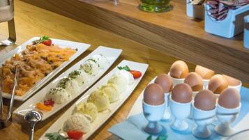 A buffet table with various food items including salads, eggs, and a bottle of oil.