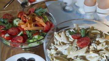 Una mesa de buffet con diversos platos, incluyendo ensalada, pasta y huevos.