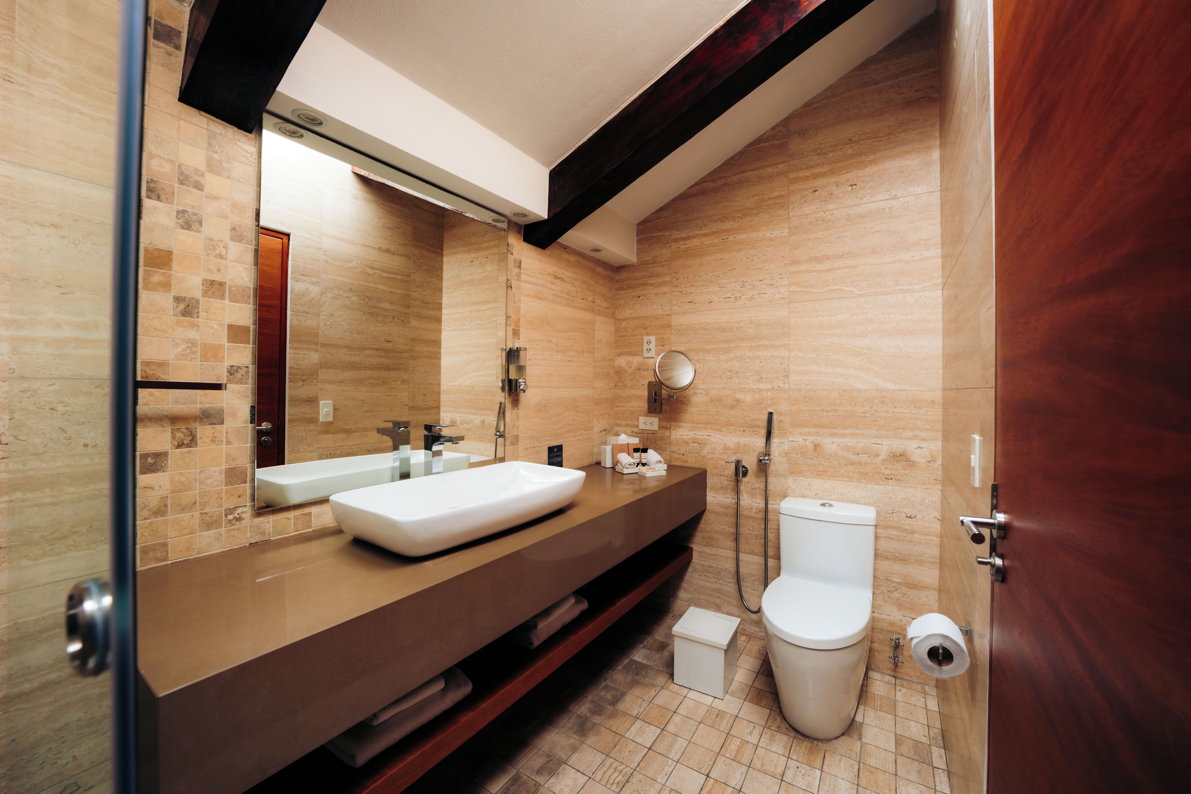 A modern bathroom with a large mirror, a sink, a toilet, and a shower.