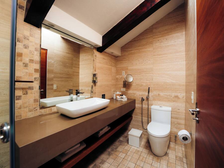 A modern bathroom with a large mirror, a sink, a toilet, and a shower.