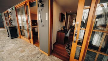 En hotelindgang med en glasdør, en trætrappe og et synligt interiør med en seng og et badeværelse.