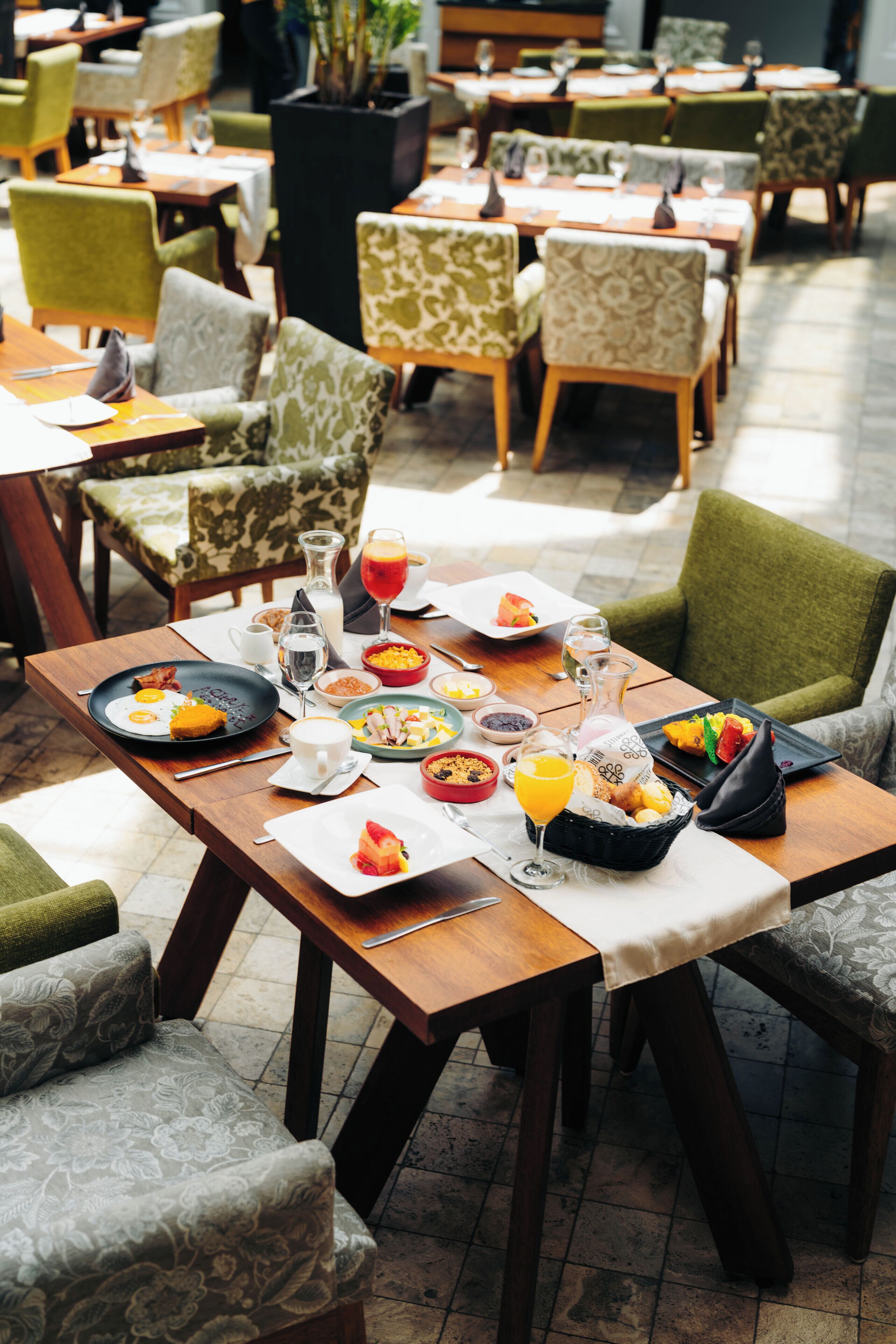A dining area with multiple tables, chairs, and a variety of dishes and drinks.